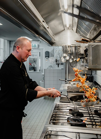 Chefkok aan het werk in de open keuken van restaurant in Den Haag