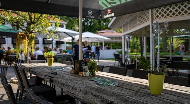 Lang houten terras met planten en zitplaatsen in Den Haag onder parasols